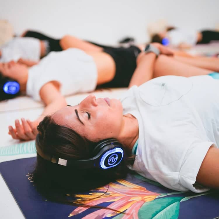inspirafit Femmes allongées avec casques sans fil pendant un cours de Silent Fitness