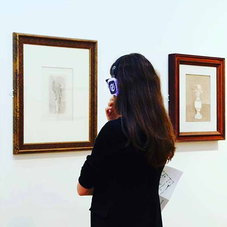 museo-milano Visiteuse d'un musée à Milan avec casque sans fil devant un tableau