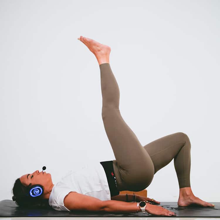 paola-inspirafit Instructrice faisant des exercices au sol avec casque sans fil
