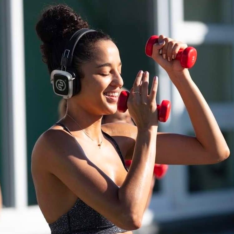 pilates Jeune femme s'entraînant avec des haltères et un casque sans fil