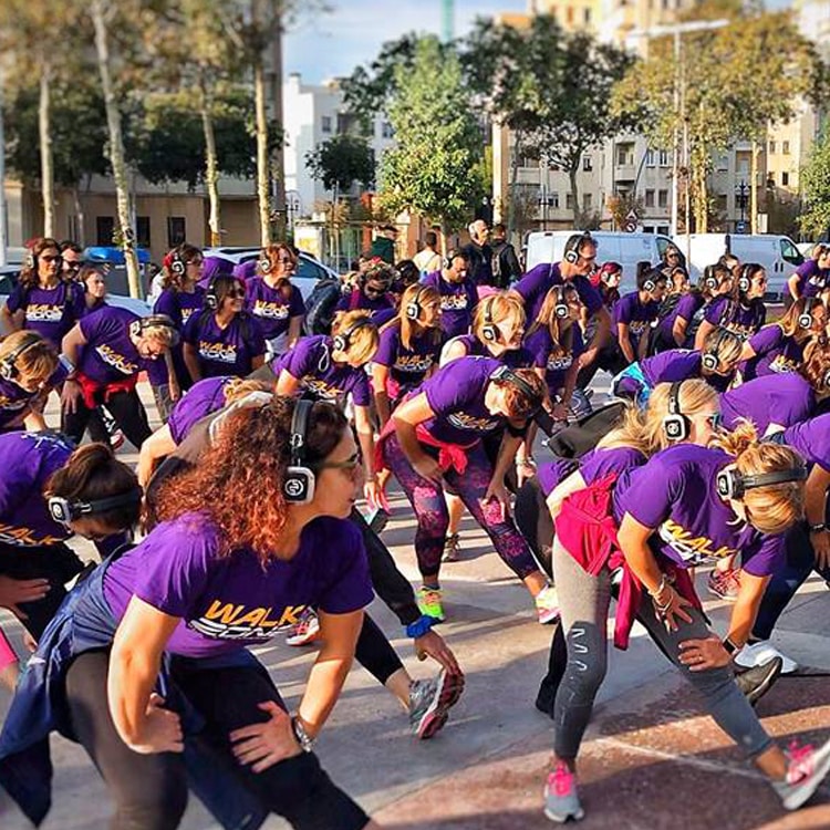 Walkzone straatfitness Grote straatfitnessgroep op een plein met draadloze hoofdtelefoons