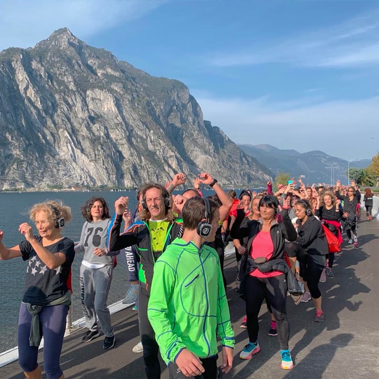 camminata-lago-cuffie Silent Walk-groep met draadloze hoofdtelefoons aan de oever van een meer