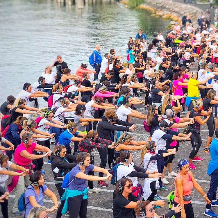 walkzone Grote fitnessgroep met hoofdtelefoons langs een rivier